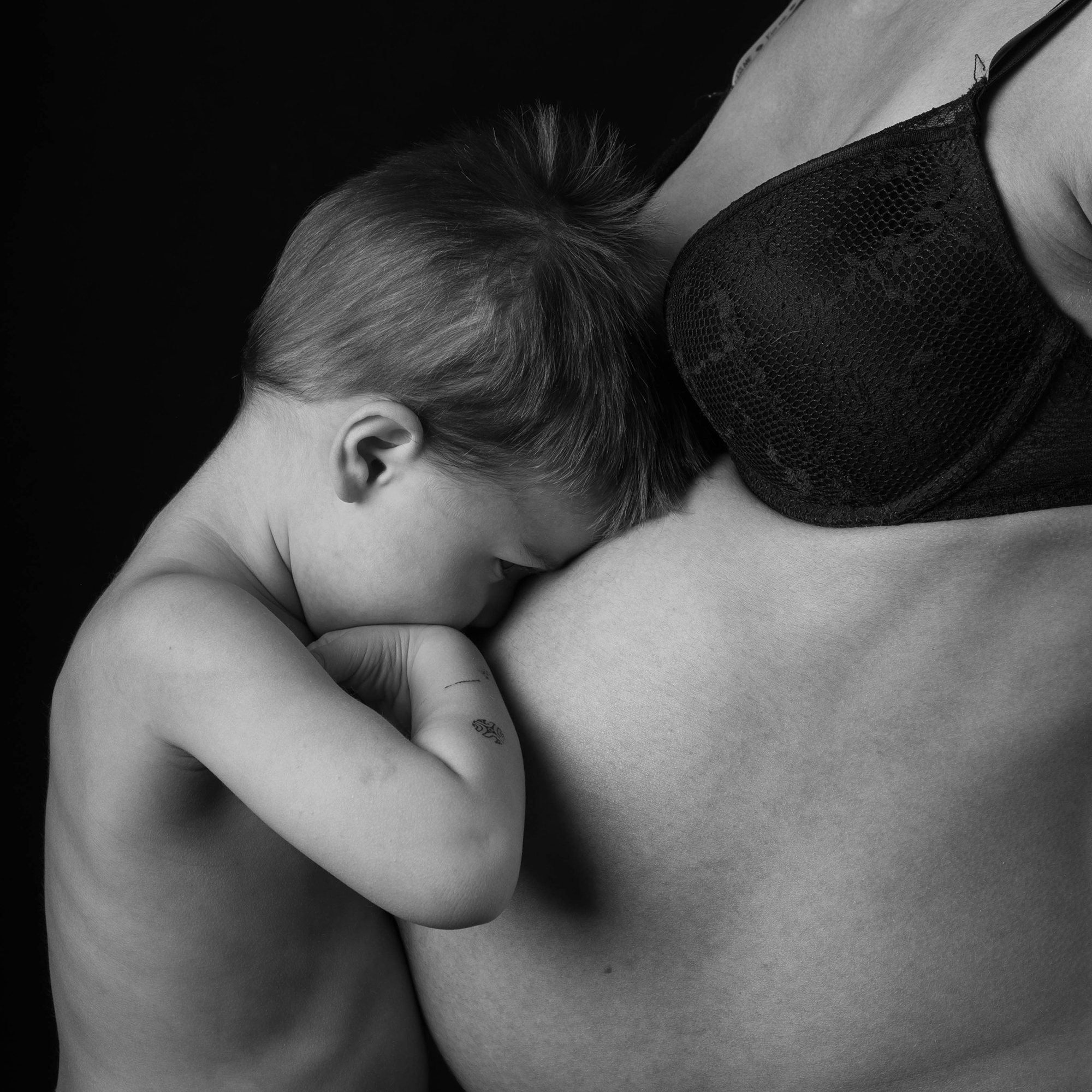 photo noir et blanche d'un enfant se cachant contre le ventre de sa maman enceinte