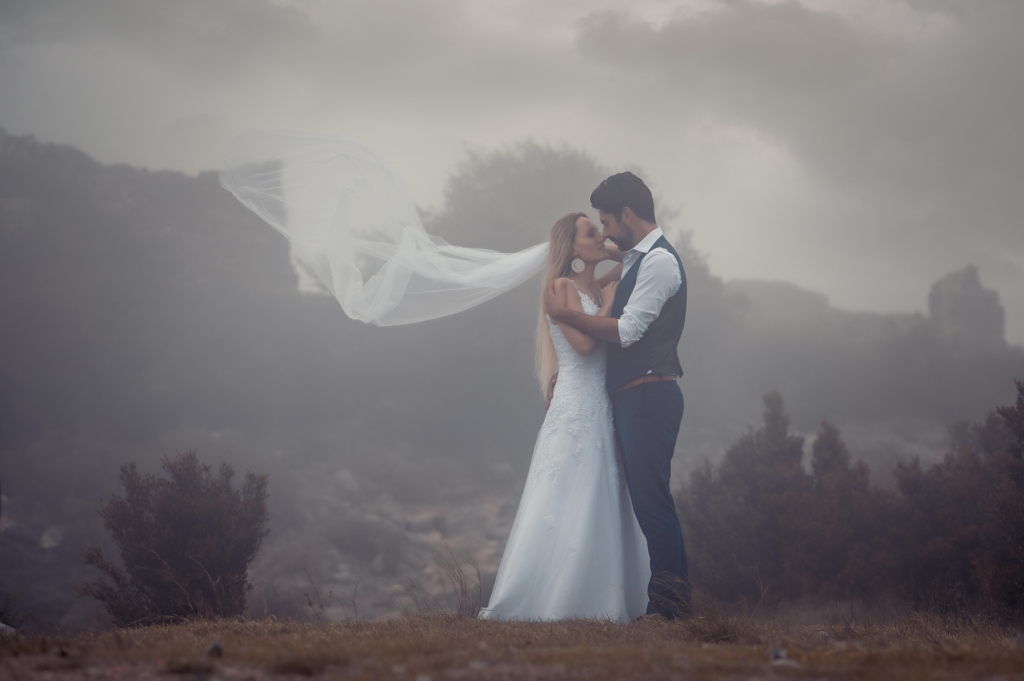 Photo d'un couple de jeunes mariés prise dans le brouillard, s'enlaçant et se regardant dans les yeux