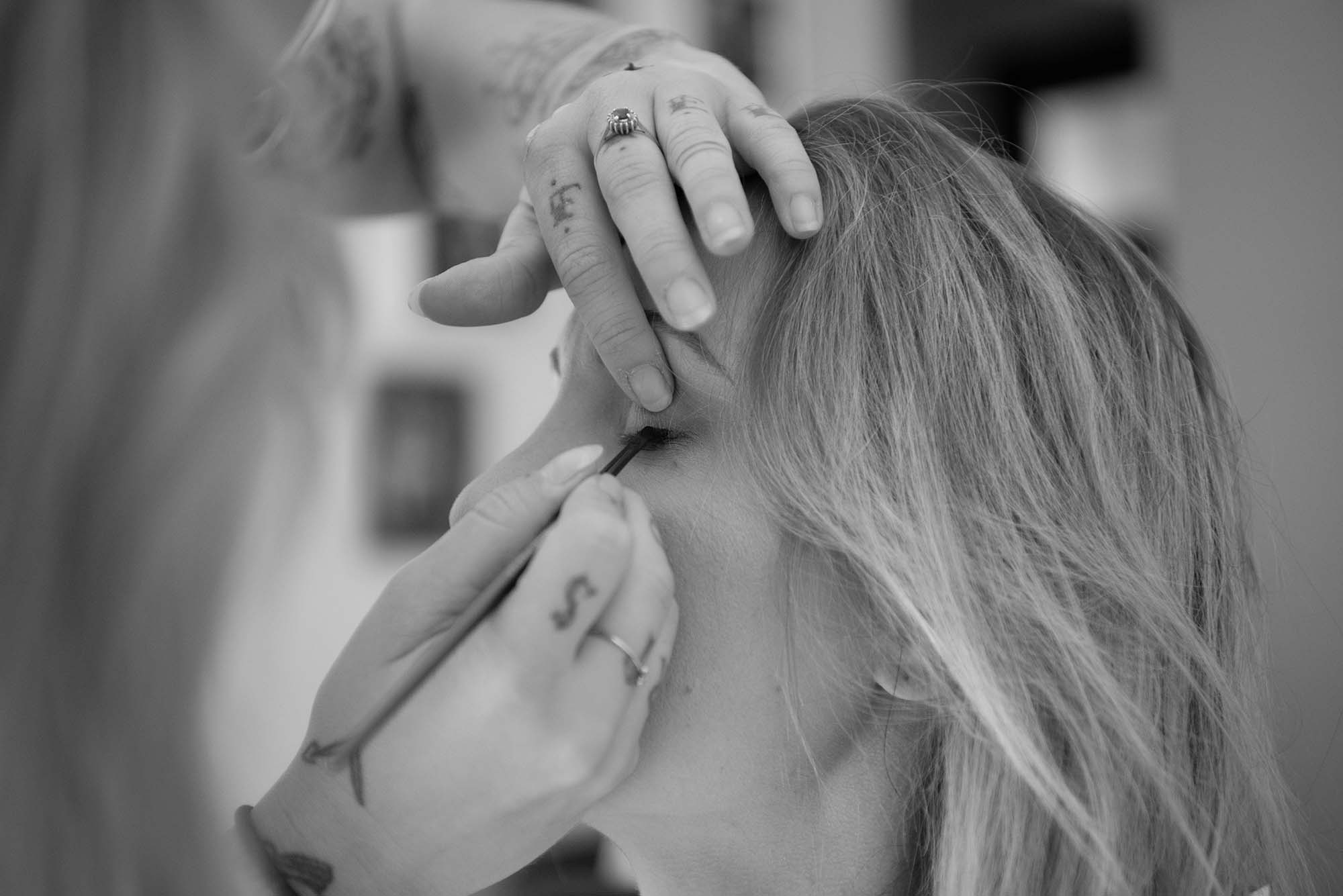 photo noir et blanc d'une femme en train de se faire maquiller les yeux