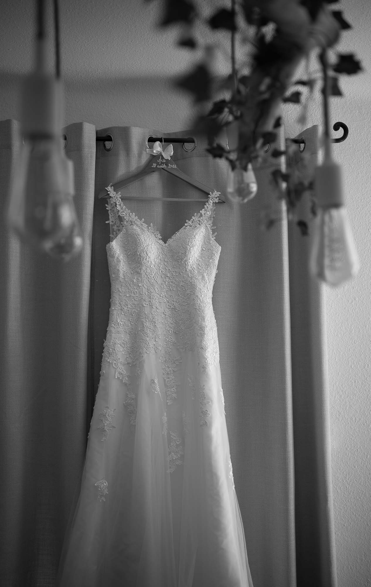photo noir et blanc d'une robe de marié accrochée sur une tringle à rideaux