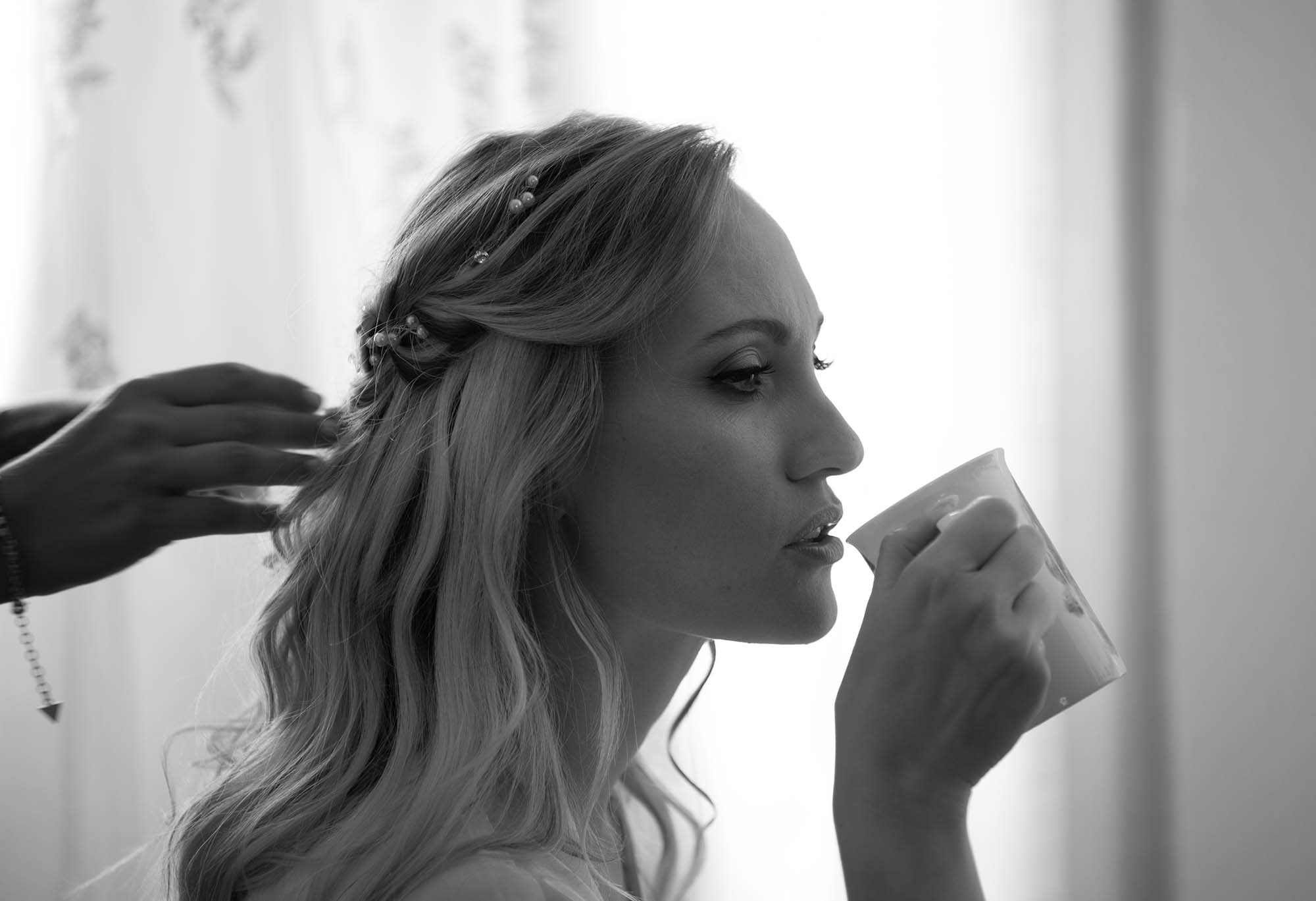 photo noir et blanc d'une femme en train de se faire coiffer un mug à la main