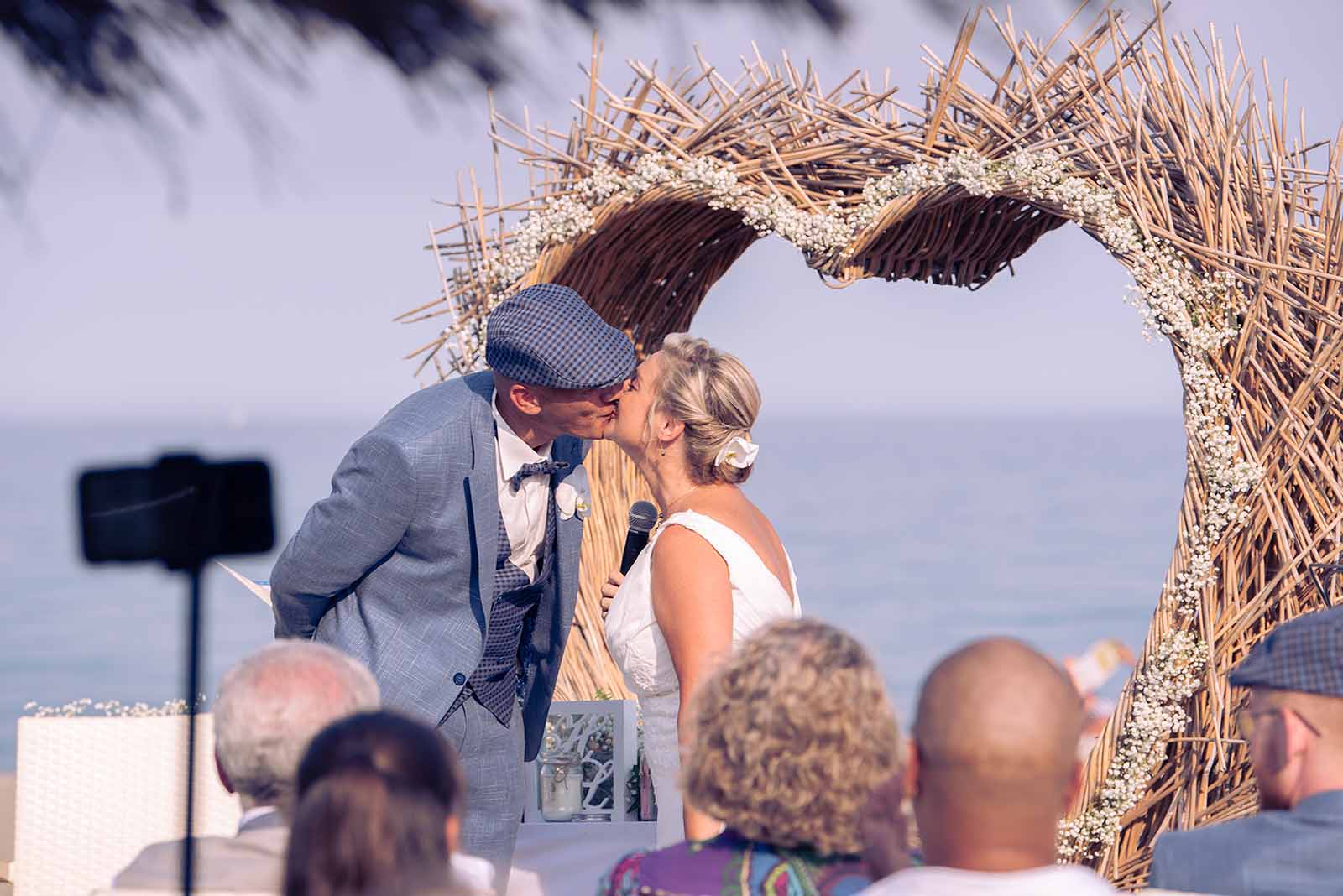 deux mariés s'embrassant lors d'une cérémonie laïque à la plage