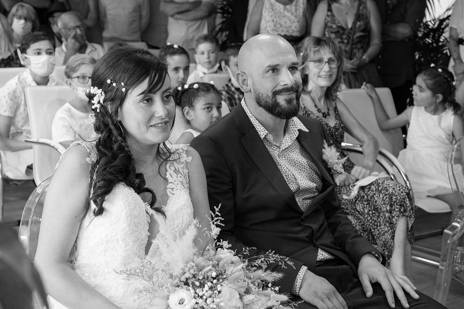 photo noir et blanc d'un couple de mariés assis lors de la cérémonie civile de leur mariage