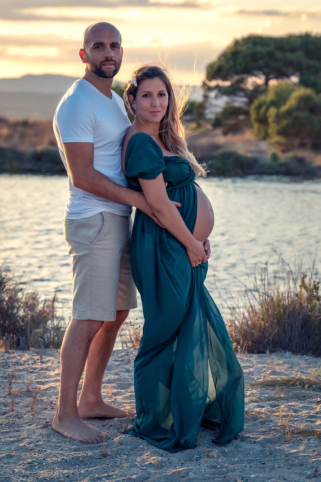 portrait d'un couple dont la femme est enceinte au coucher de soleil et au bord de l'eau