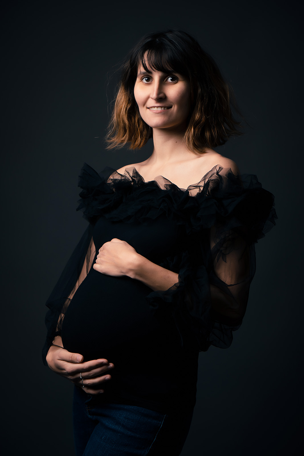 femme enceinte aux cheveux cours habillée avec un top noir et froufrou en tulle