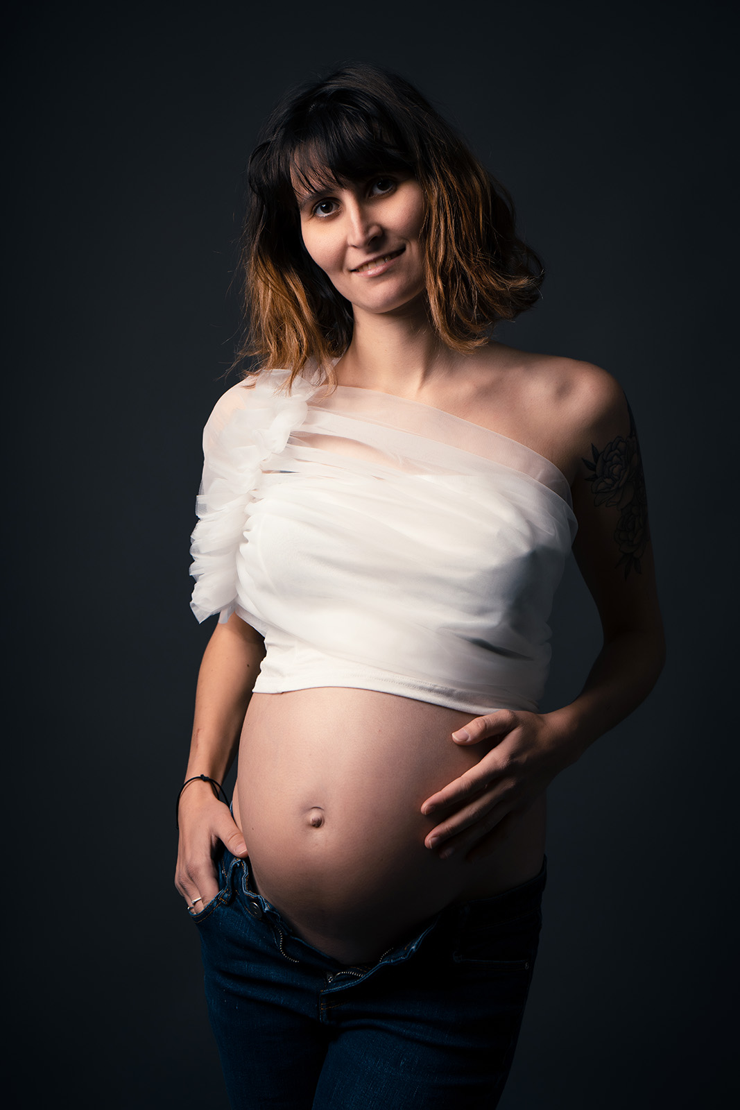 femme enceinte aux cheveux cours habillée avec un crop top blanc avec du tulle