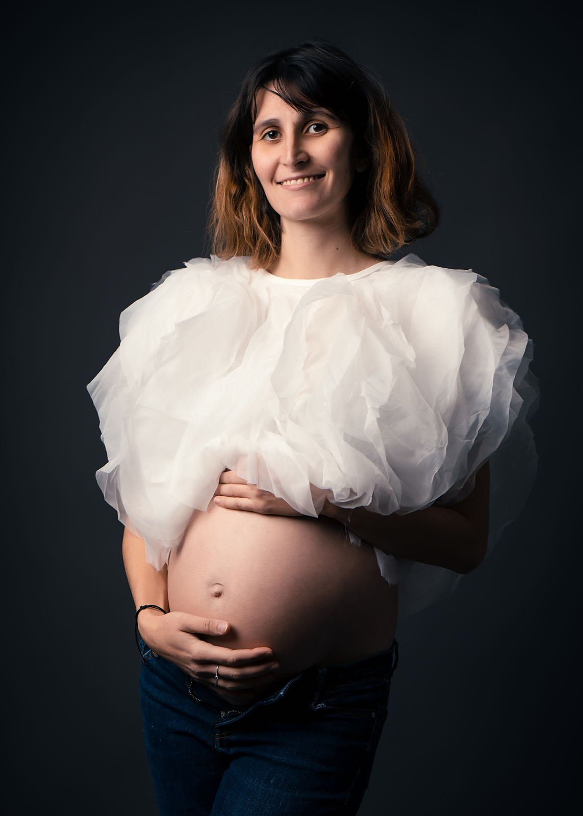 femme enceinte aux cheveux cours habillée avec un crop top blanc volumineux