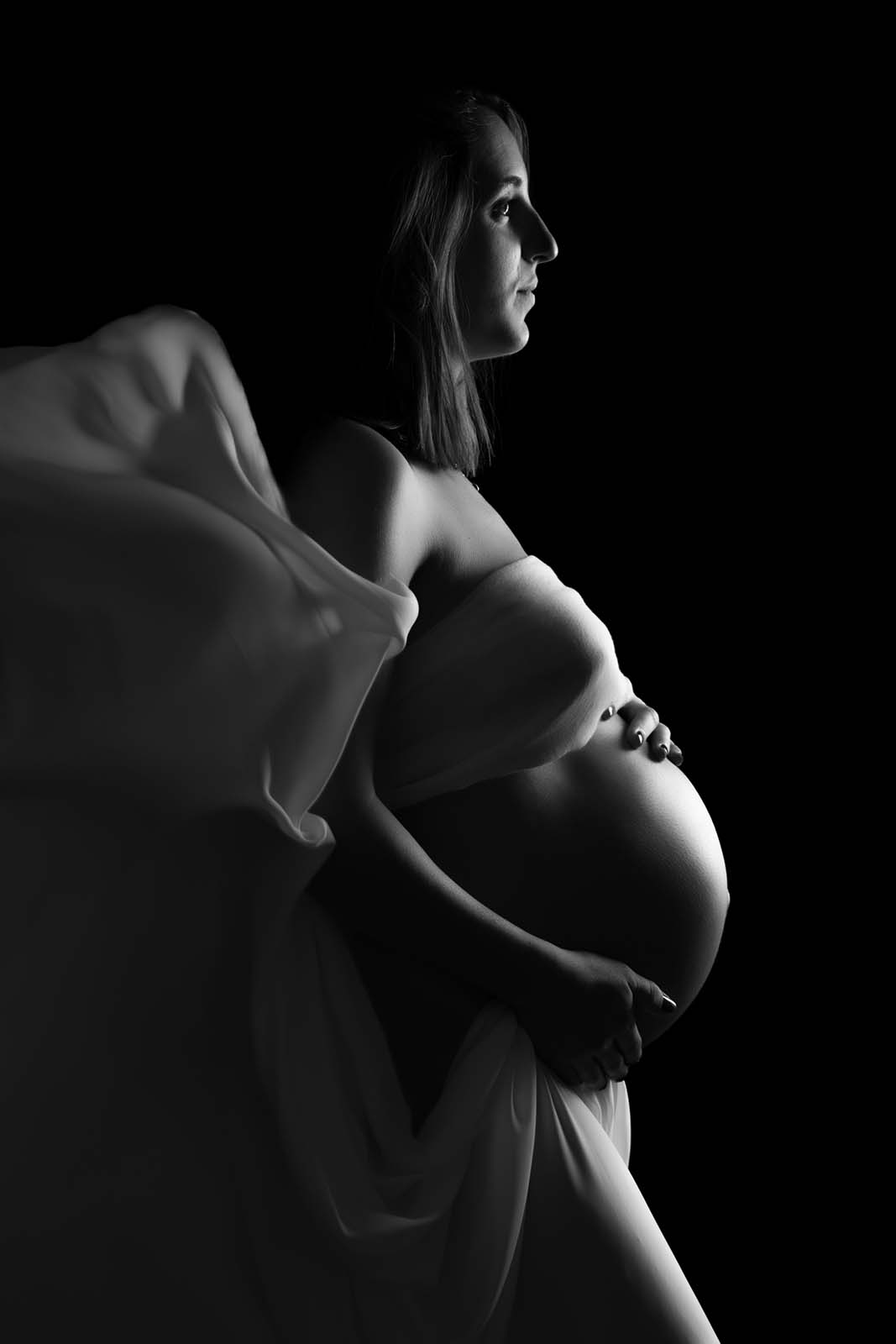 photo noir et blanc d'une femme enceinte qui est habillée d'un voile blanc volant