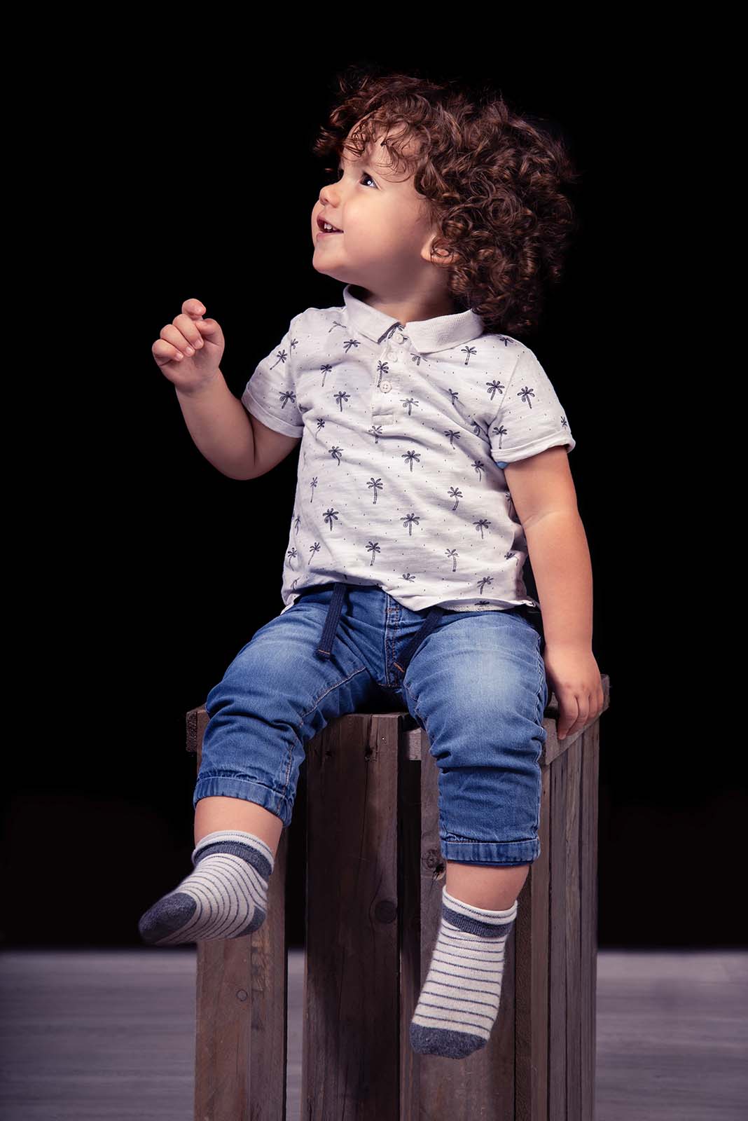 portrait d'un petit garçon assis sur une caisse en bois