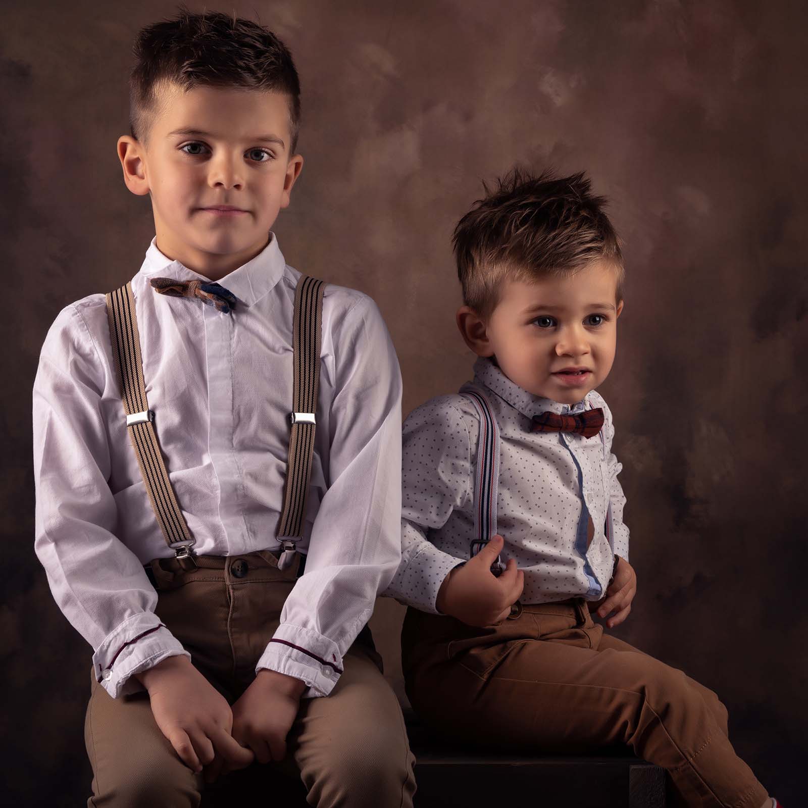portrait de deux jeunes garçons habillés avec des bretelles et une chemise blanche