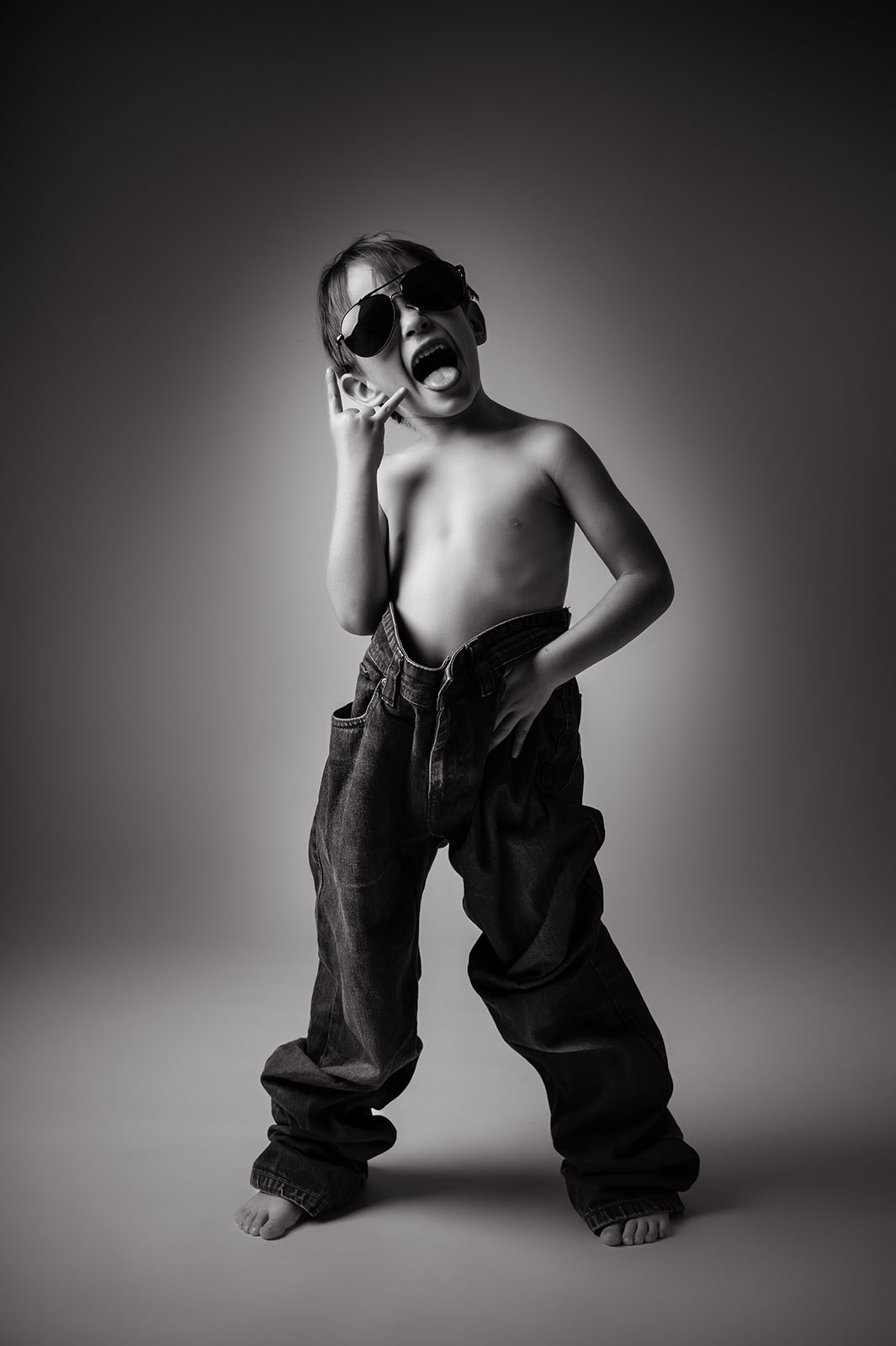portrait d'un petit garçon en noir et blanc portant un jean et de lunettes de soleil