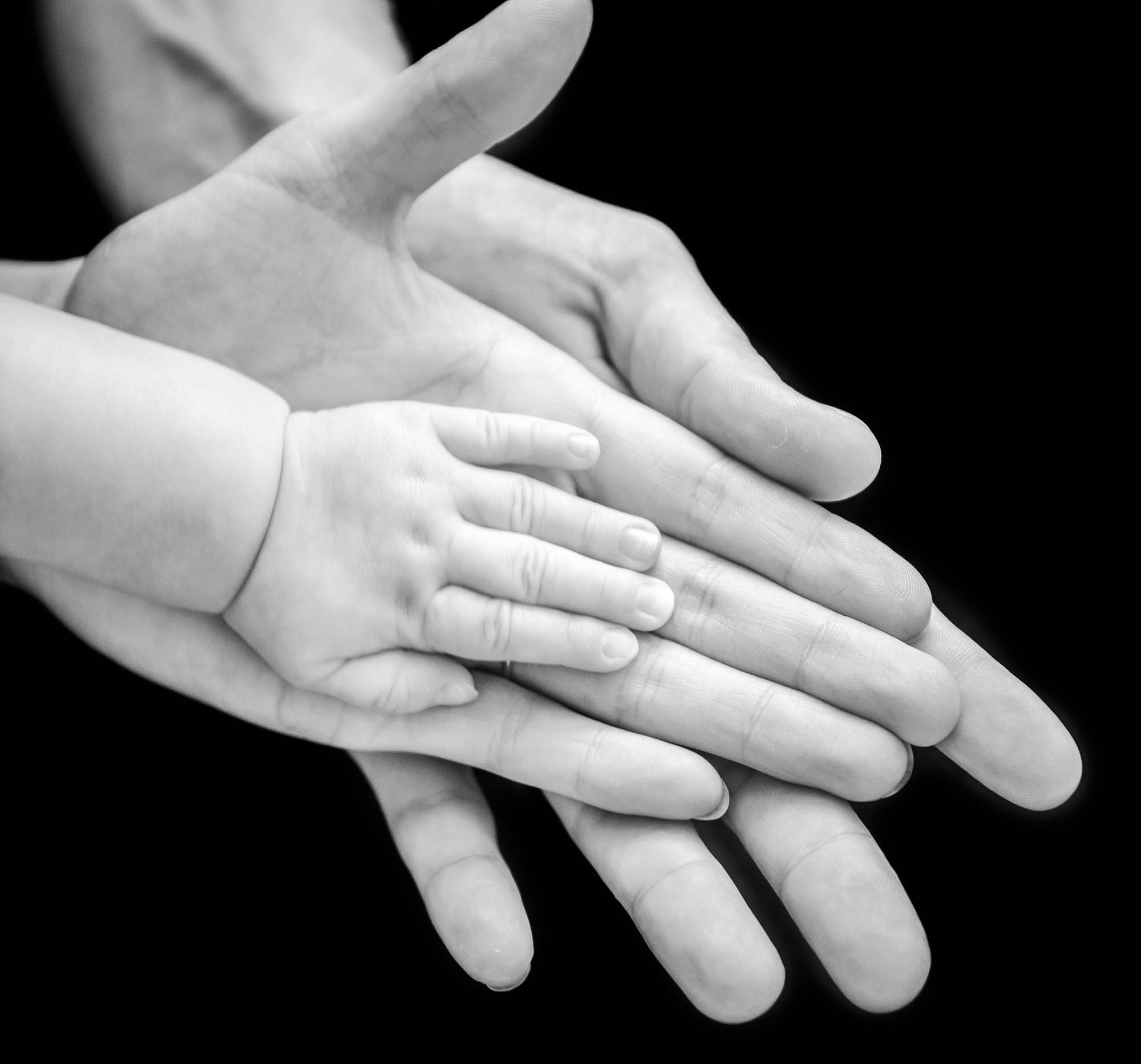 photographie noir et blanche de la main d'un bébé et de ses parents superposées