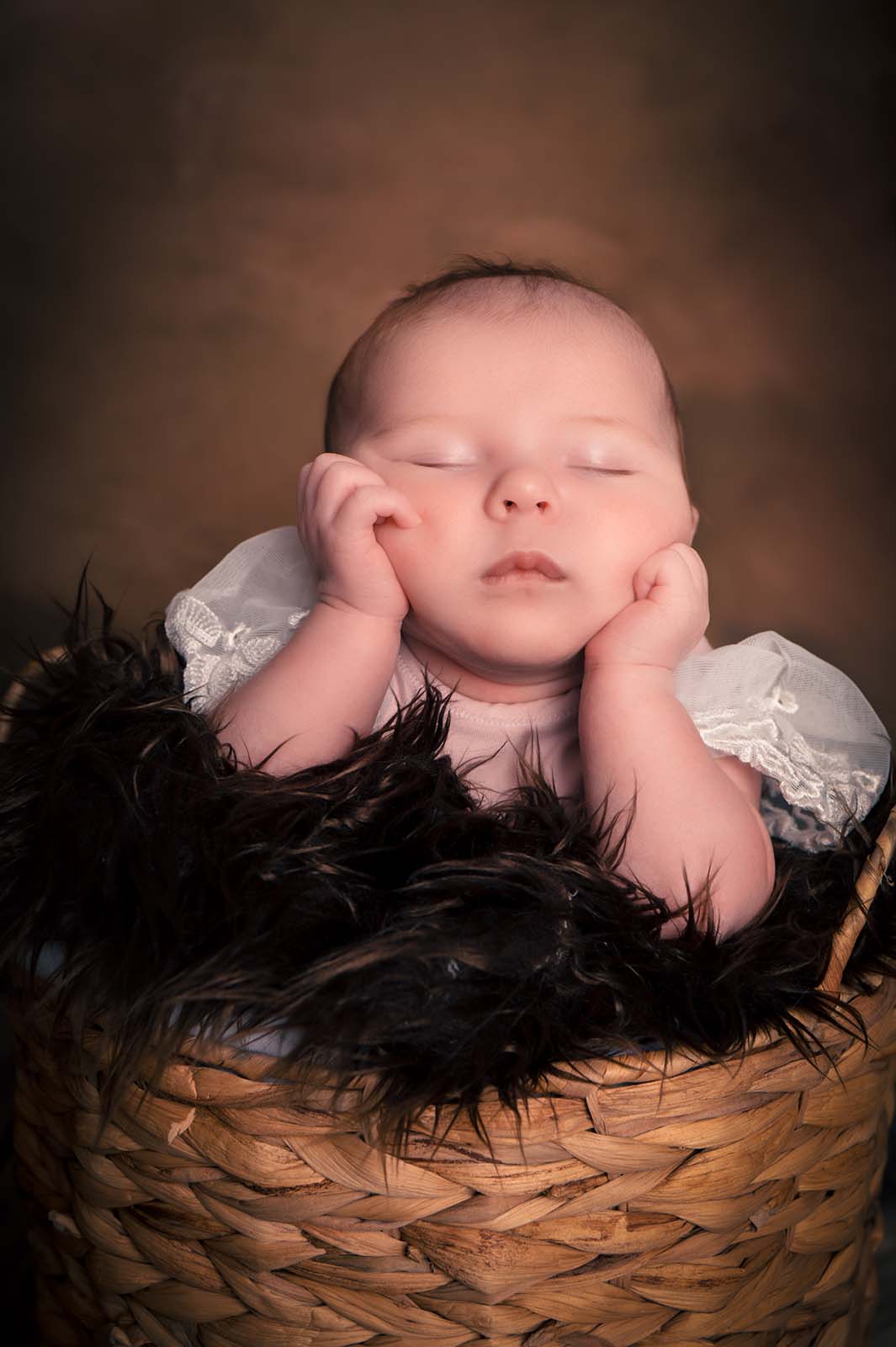 photo d'un bébé se tenant la tête avec les points fermés dans un contenant en osier