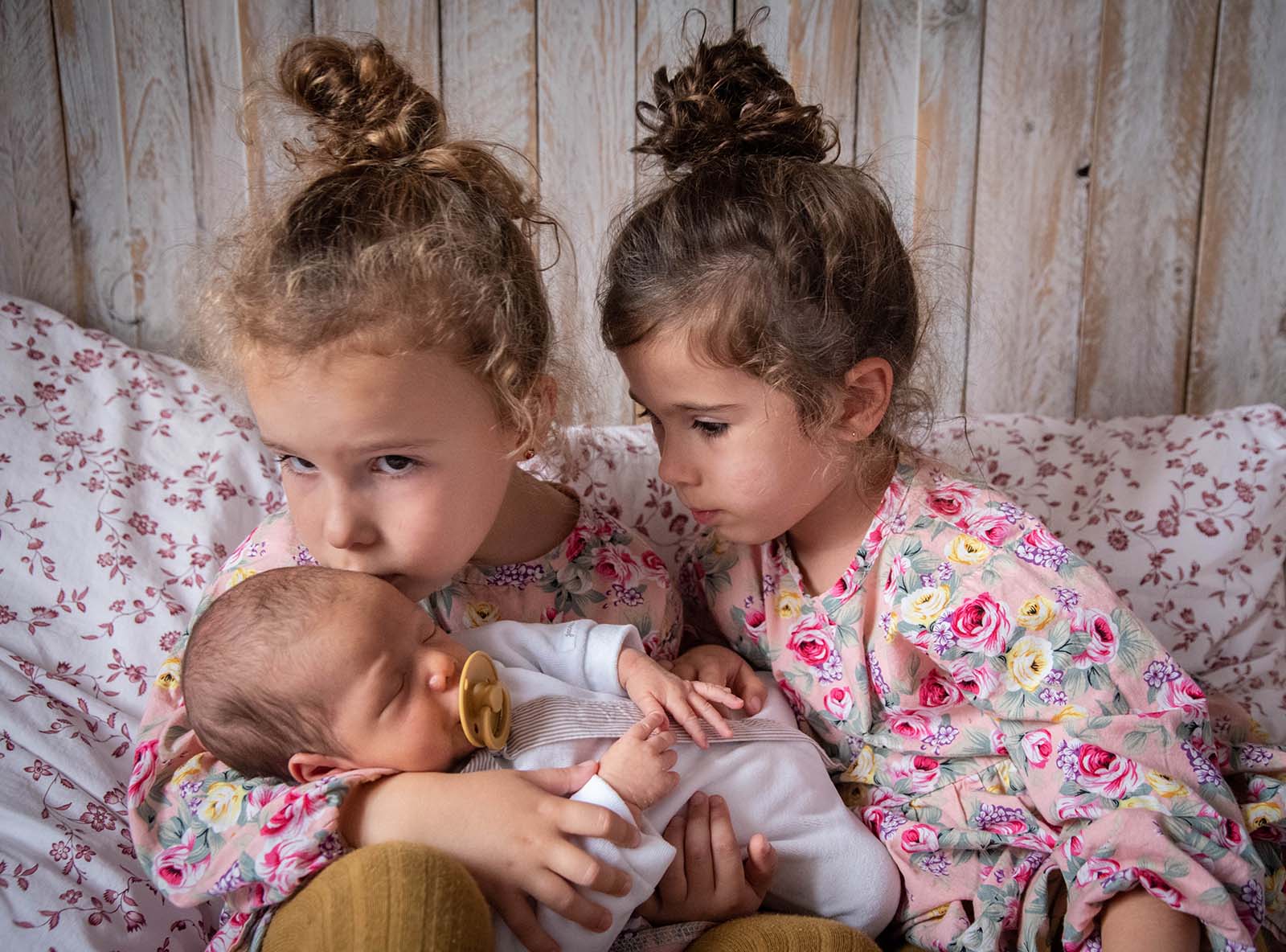 portrait de deux petites filles tenant un nourrisson dans les bras