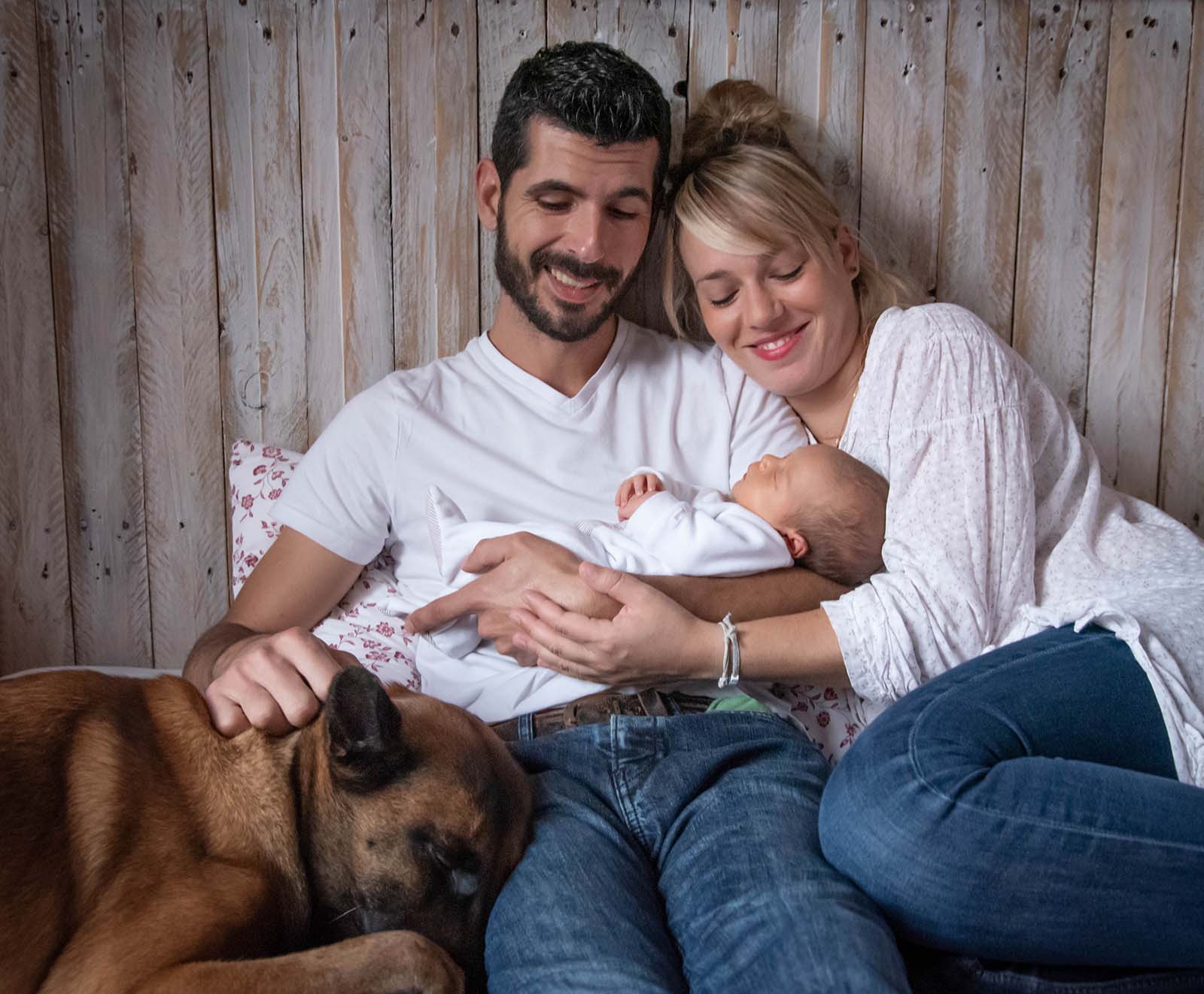 portrait d'un couple avec un chien et qui tient un bébé dans les bras