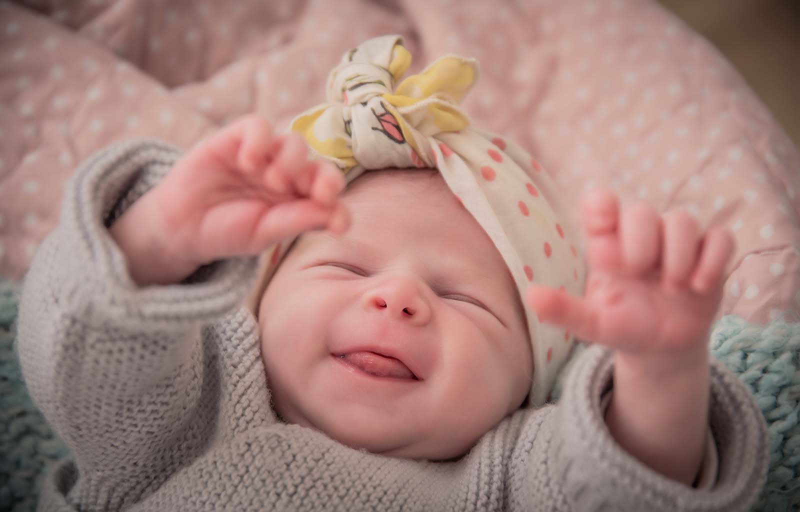 portrait d'un bébé avec un nœud sur la tête et levant les bras