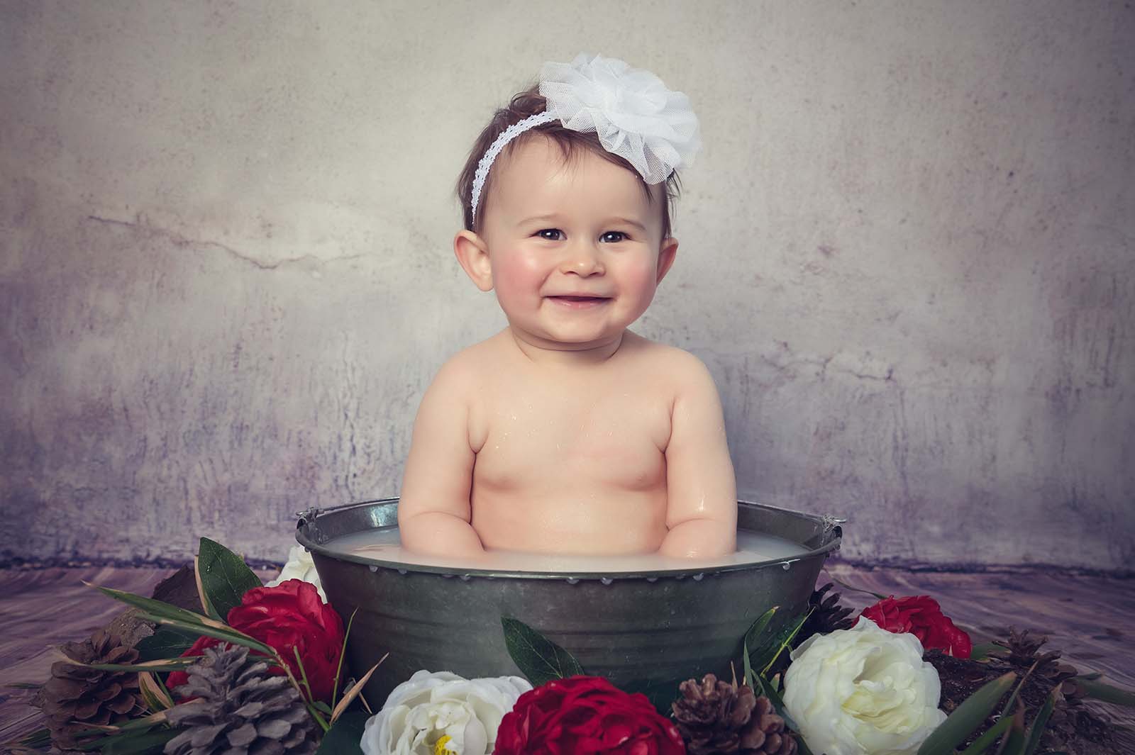 portrait d'un bébé dans une bassine en zinc lors d'une séance photo bain de lait