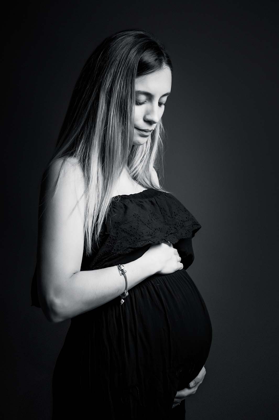 photo noir et blanc d'une femme enceinte vêtue d'une robe noire