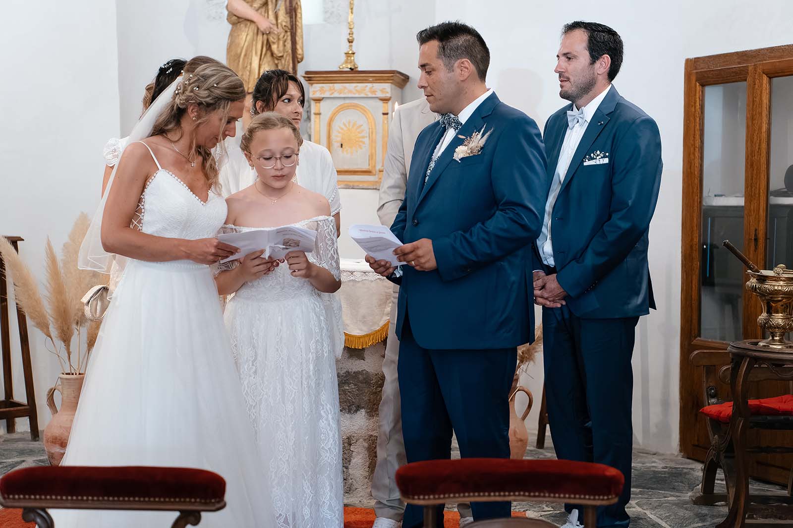 une jeune fille lisant un document entourée des mariés à l'église