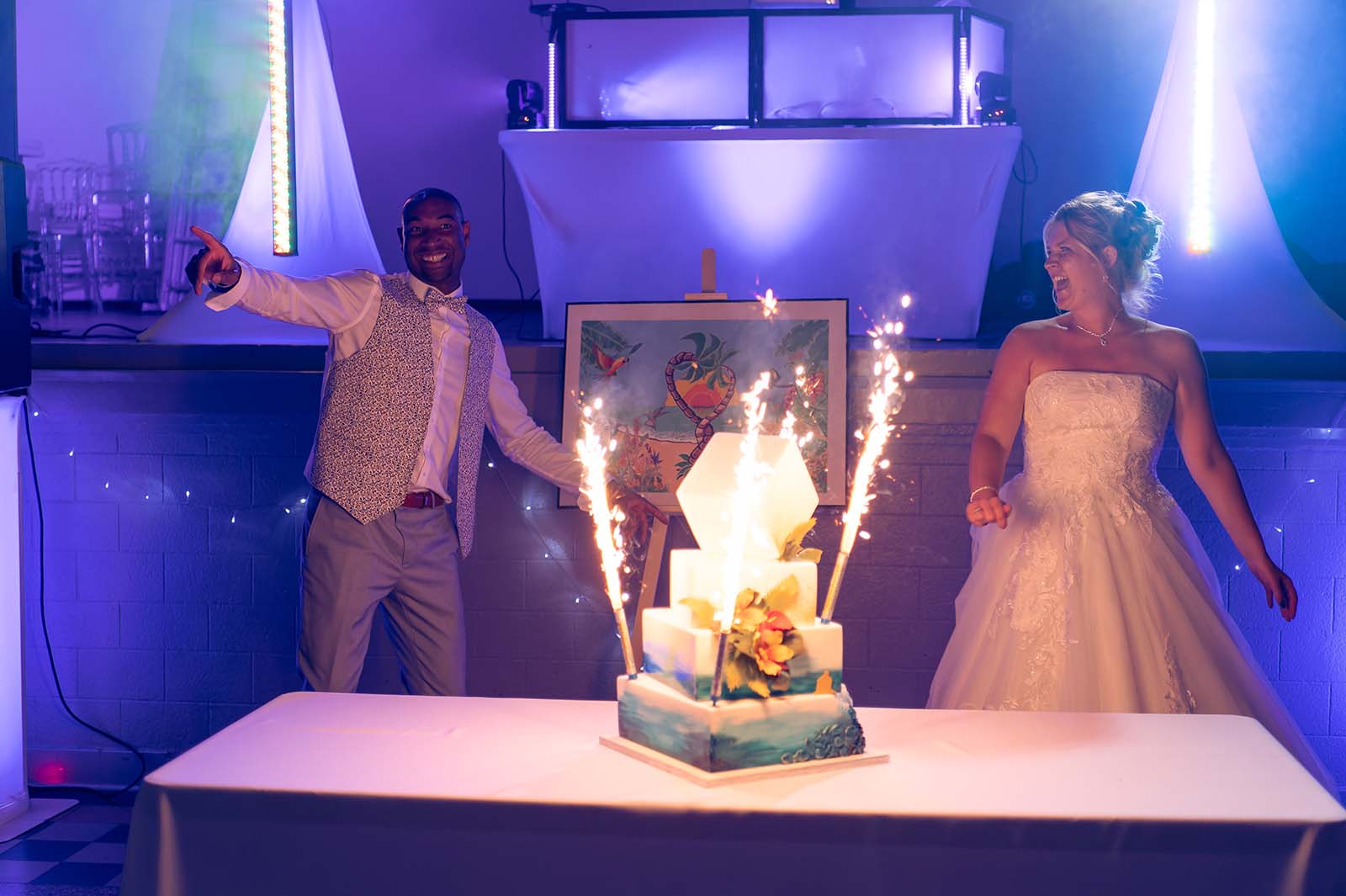mariés devant leur gâteau posé sur une table avec des étincelles