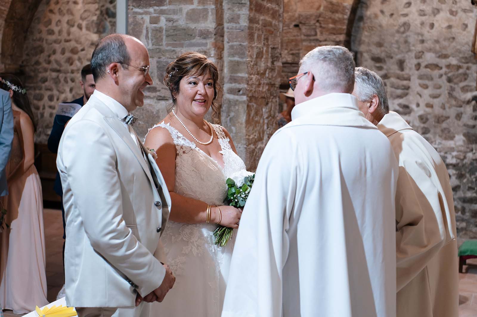 couple de mariés se tenant fasse au prêtre lors de la cérémonie religieuse d'un mariage