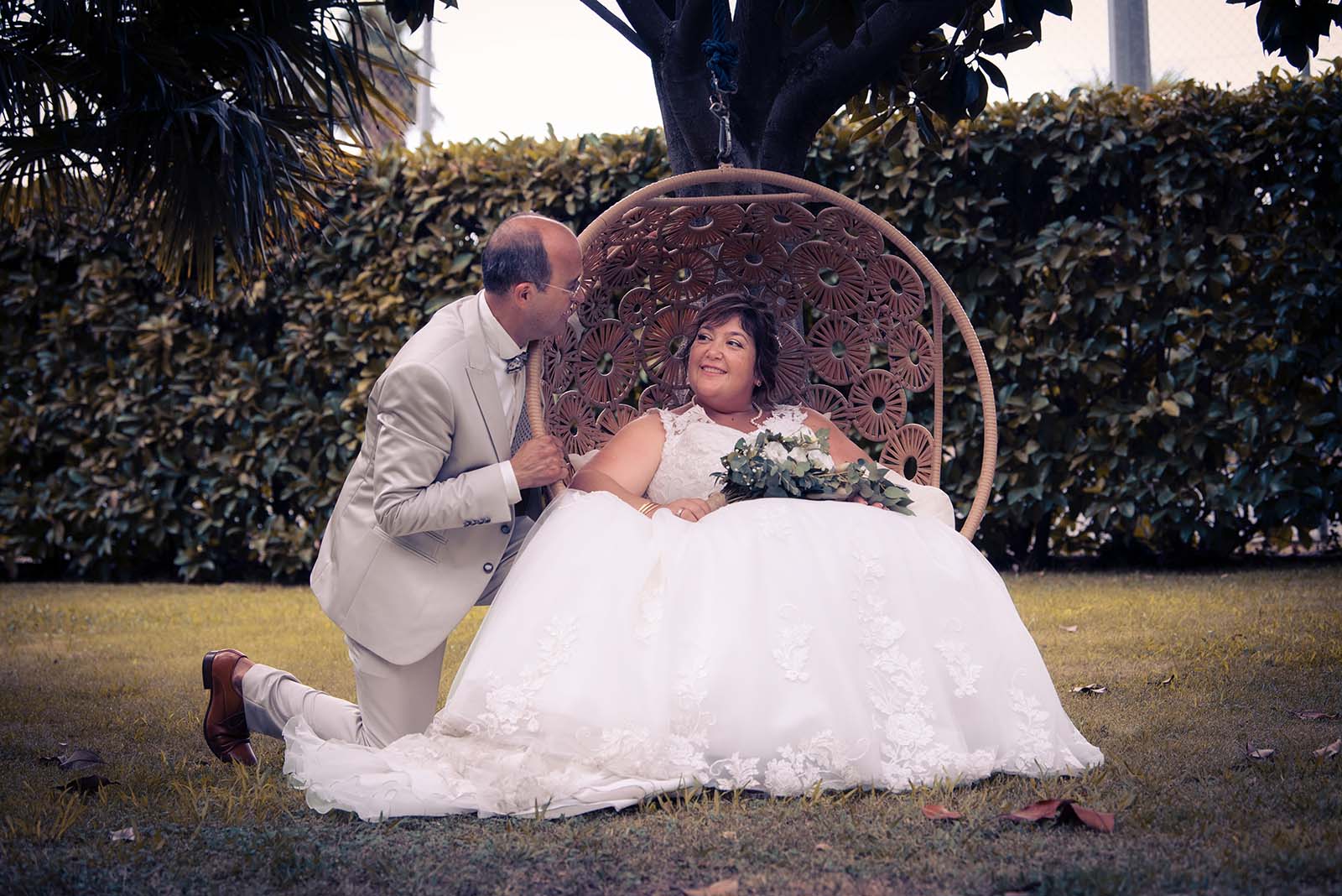 photo de couple de jeunes mariés, la mariée est assise dans un gros fauteuil