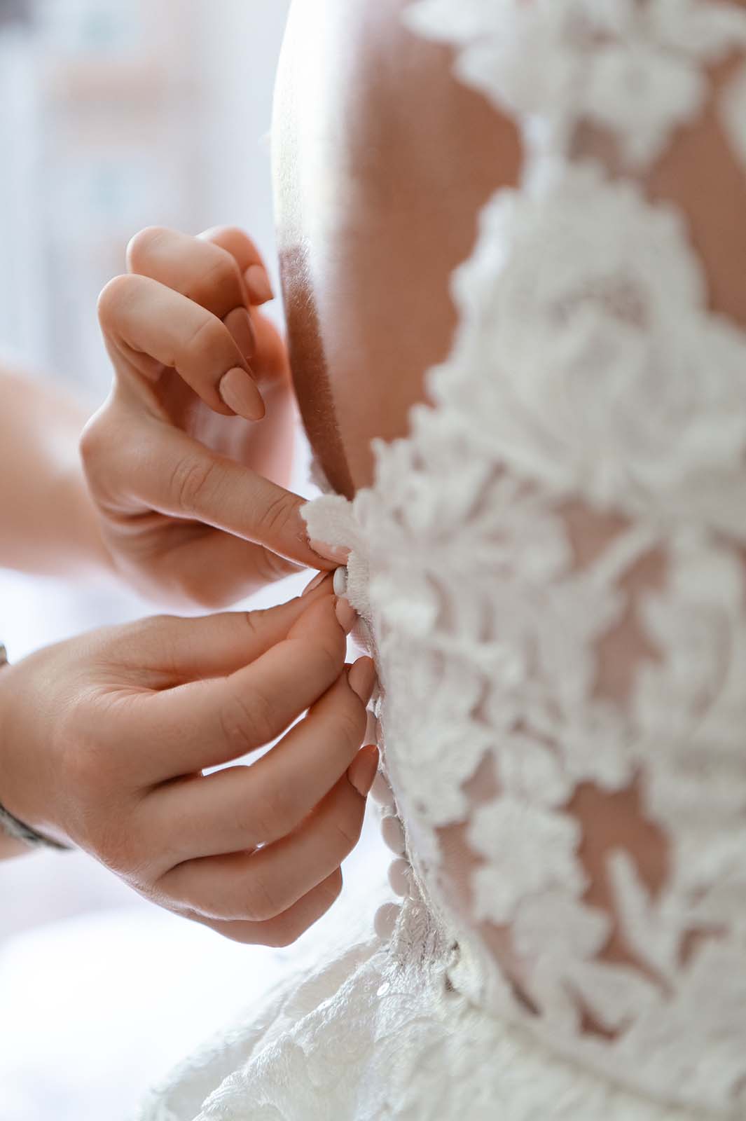 gros plans sur des doigts en train de boutonner des boutons sur une robe de mariée