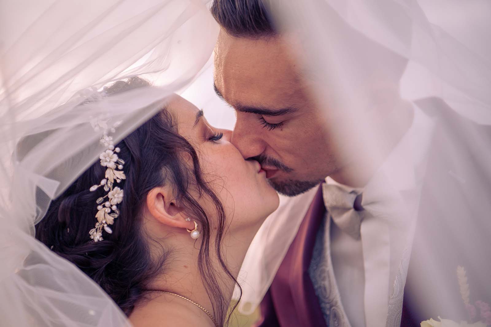 couple de marié s'embrassant sous un voile