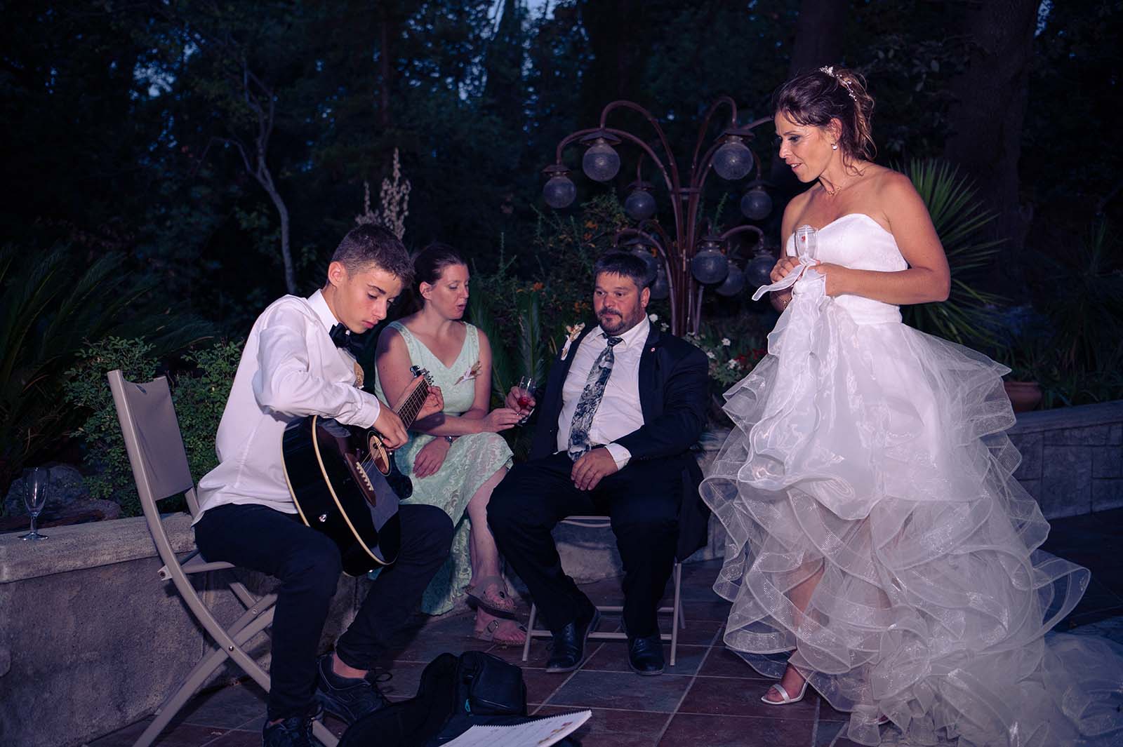 une jeune homme joue de la guitare et une mariée le regarde