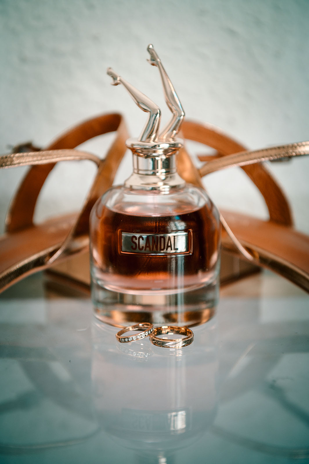 bouteille de parfum Scandal avec deux alliances devant posées sur une table en verre