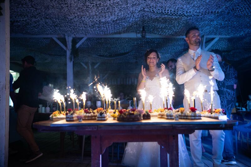 photo d'un couple de mariés derrière leur gâteau de mariage