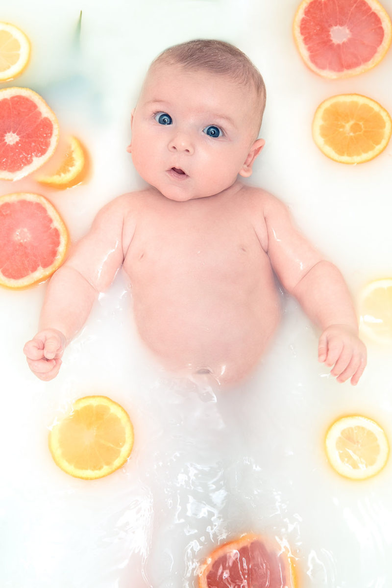 bébé dans un bain de lait avec des agrumes qui flottent
