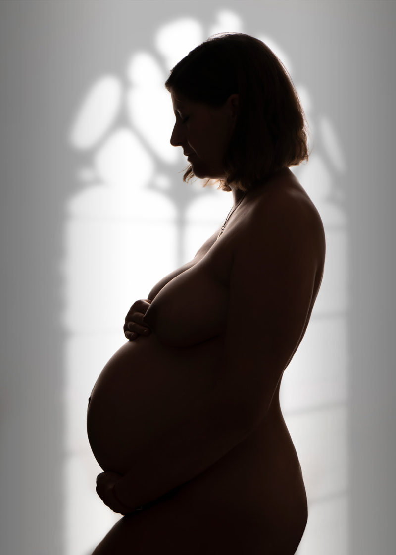 photo d'une femme enceinte en contre jour avec une ombre de fenêtre derrière