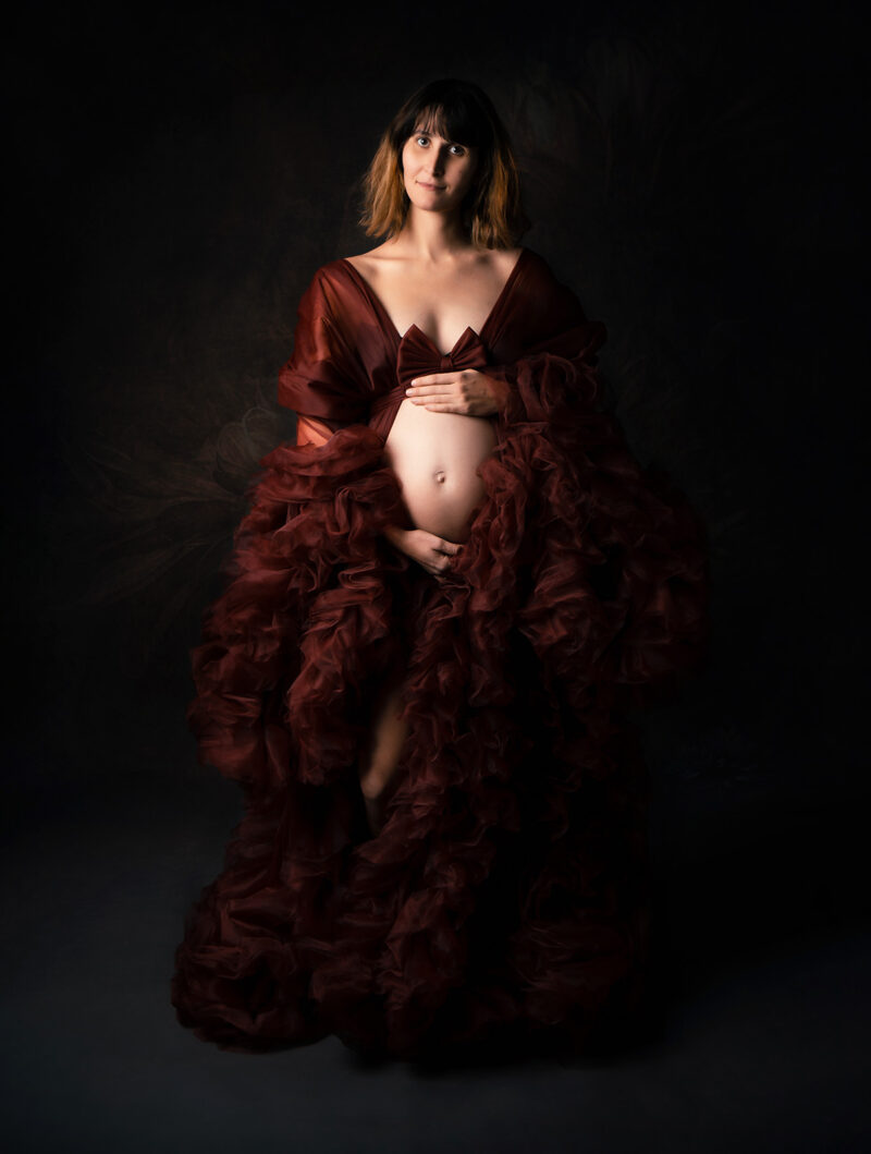 photo studio d'une femme enceinte blonde dans une robe en tulle de couleur bordeaux