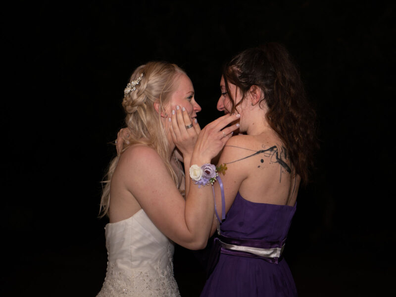 photo d'une mariée et d'une jeune fille en train de se prendre les visage dans les mains