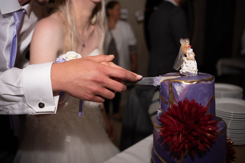 Gros plan sur des mains de mariés en train de couper leur gâteau