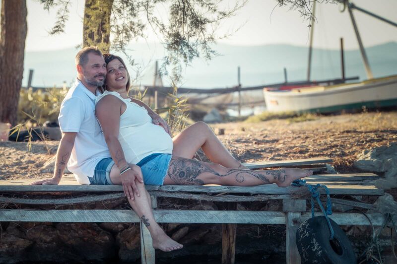 photo d'un couple habillé en jean et haut blanc assis sur un petit ponton en bois