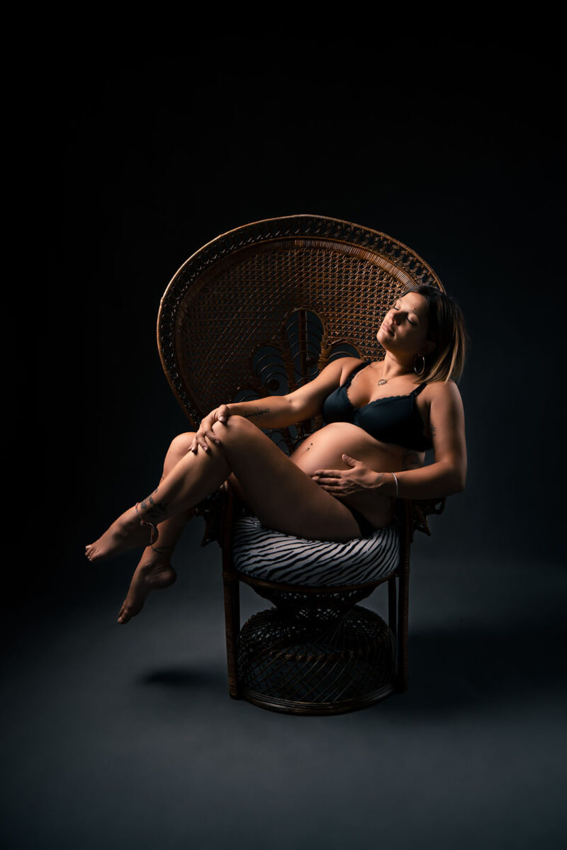 photo d'une femme enceinte en lingerie noir assise dans un fauteuil Emmanuelle