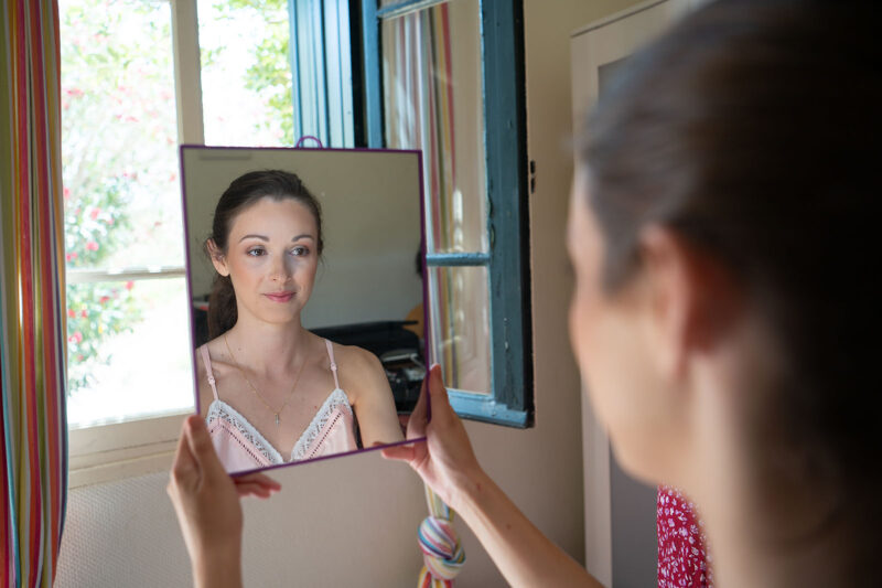 une jeune femme en train de se regarder dans un petit miroir