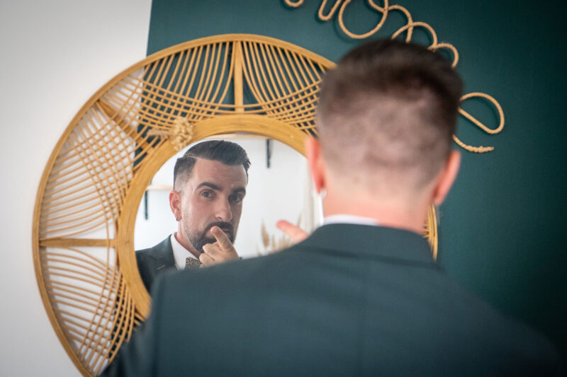 photo d'un homme en costume vert se regardant dans le miroir