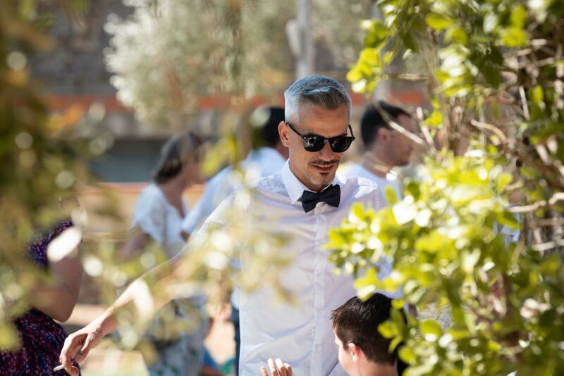 photo d'un homme en chemise blanche avec un nœud paillon noir et des lunettes de soleil