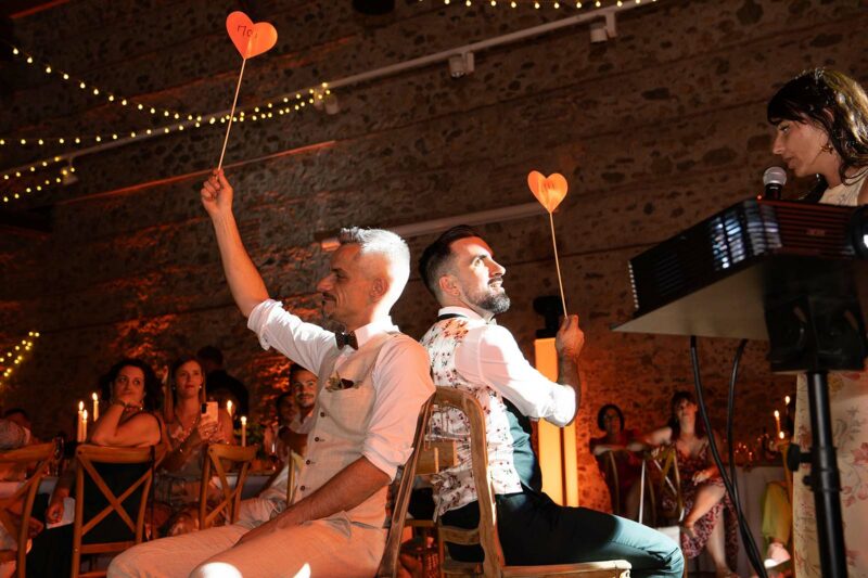 photo des mariés assis sur une chaise levant un cœur en papier