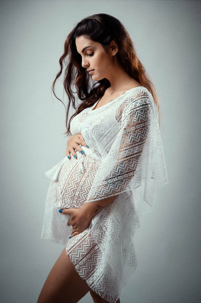 Portrait studio d'une femme enceinte habillée d'un couvre maillot blanc en dentelle