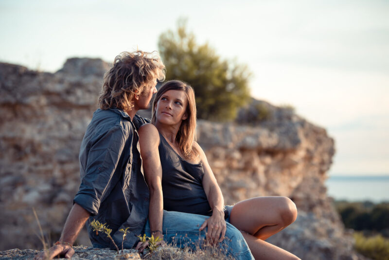 Portrait d'un couple en train de se regarder assis sur un mur en pierre