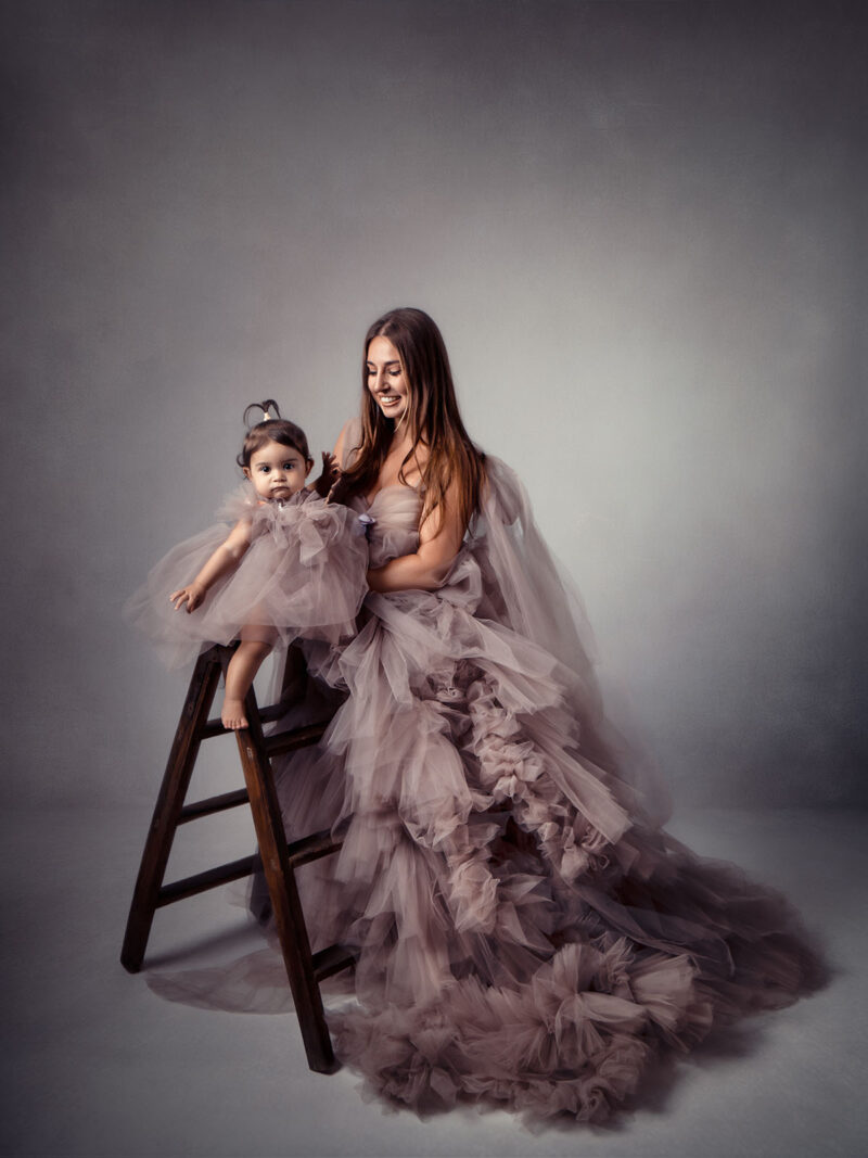 portrait studio d'une femme aux cheveux longs et de sa petite fille habillée d'une robe en tulle rose volumineuse