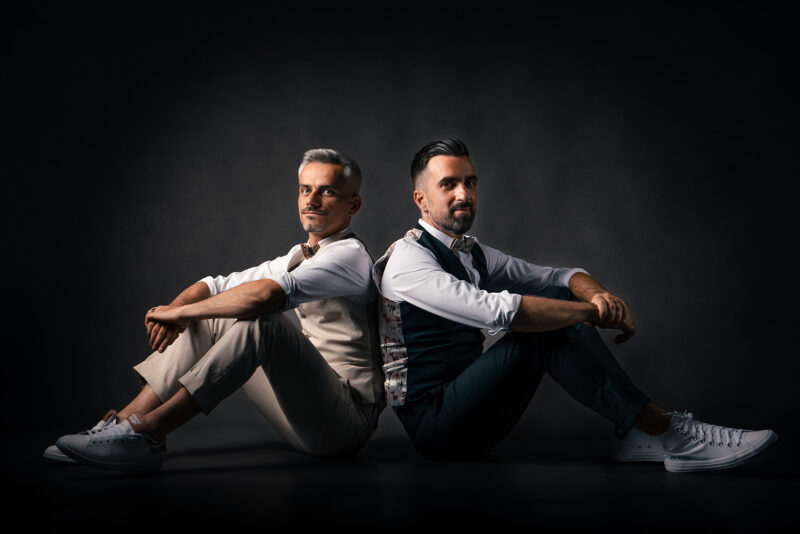 photo studio de deux hommes en costume assis au sol dos à dos