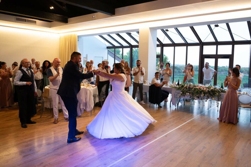 deux mariés en train de danser dans une salle applaudis par les convives