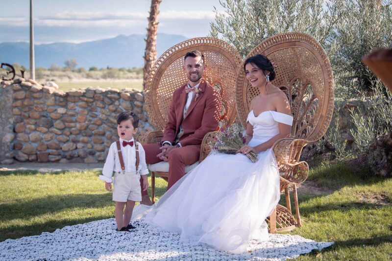 mariés assis sur un fauteuil Emmanuelle avec un petit garçon se tenant debout devant eux