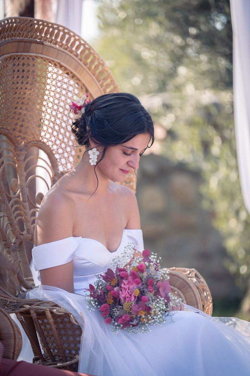 mariée assise sur un fauteuil Emmanuelle regardant son bouquet de fleurs