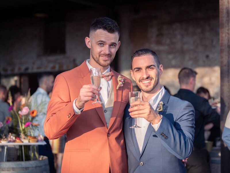 deux hommes en costumes tenant une coupe de champagne à la main